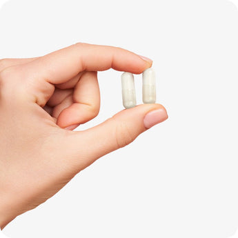 Conceive Plus Birth Control Detox capsules shown held between fingers, offering a close-up view of two transparent vegan capsules with a light beige powder inside, demonstrating actual supplement form for daily use.