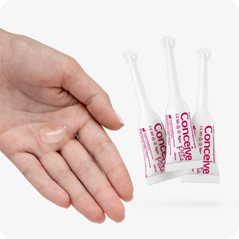 For Conceive Plus Try Me Size Bundle (30ml Tube and 3x4g Applicators), featuring a hand with a small amount of clear fertility lubricant gel, positioned next to three 4g pre-filled fertility lubricant applicators standing upright, all set against white background.